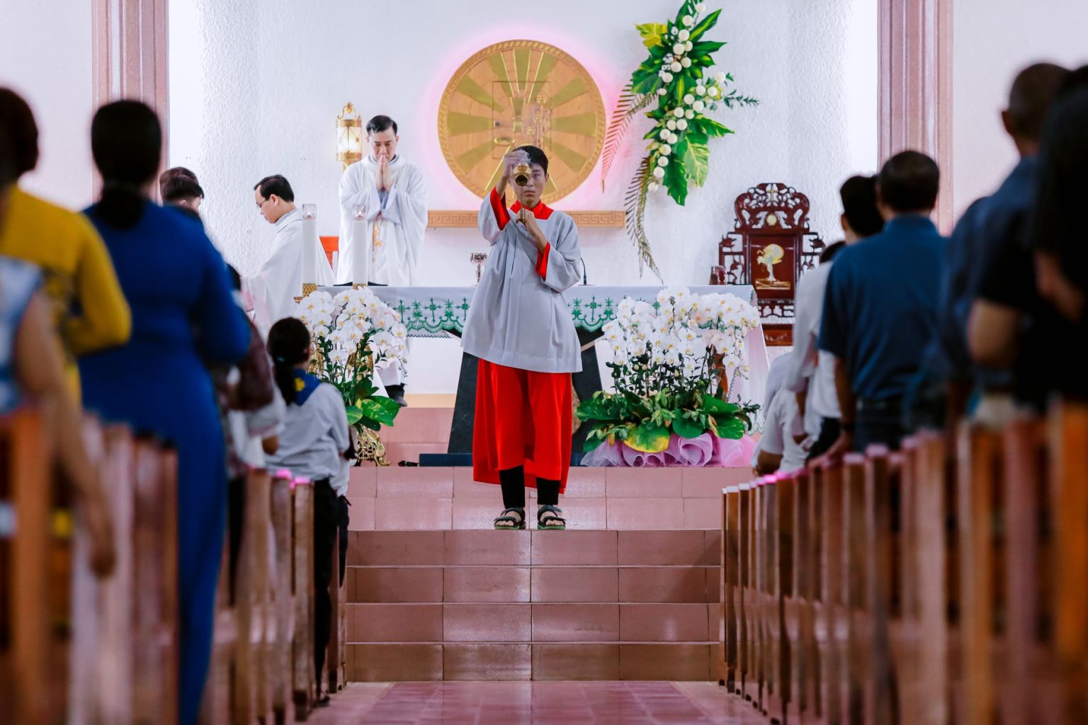 Padre conduz celebração religiosa diante de fiéis reunidos no interior de uma igreja.