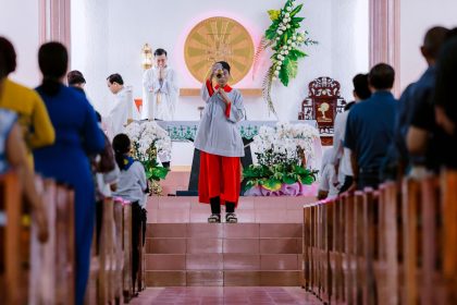 Padre conduz celebração religiosa diante de fiéis reunidos no interior de uma igreja.