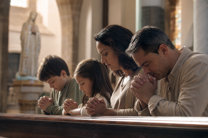 Família participa de momento de oração em uma igreja católica