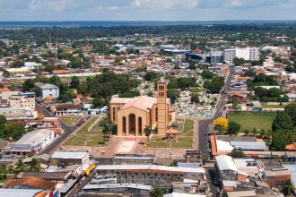 Vista aérea de uma igreja católica em meio à paisagem urbana amazônica brasileira.