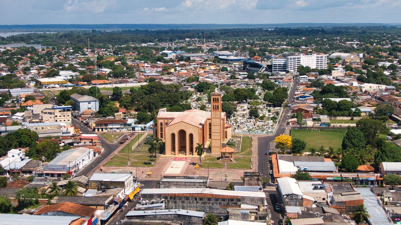 Vista aérea de uma igreja católica em meio à paisagem urbana amazônica brasileira.