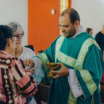 Sacerdote distribui a Eucaristia a fiéis durante uma celebração em uma igreja.