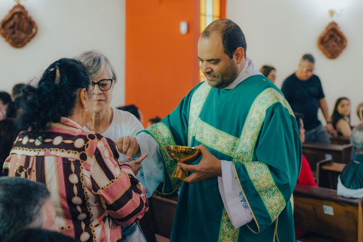 Sacerdote distribui a Eucaristia a fiéis durante uma celebração em uma igreja.