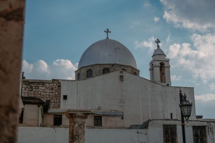 Igreja cristã histórica com cúpula e cruzes em Damasco, na Síria, sob céu claro.